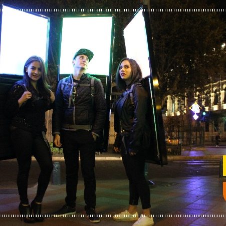 Personas con mochilas publicitarias LED encendidas en el centro de Cuenca de noche